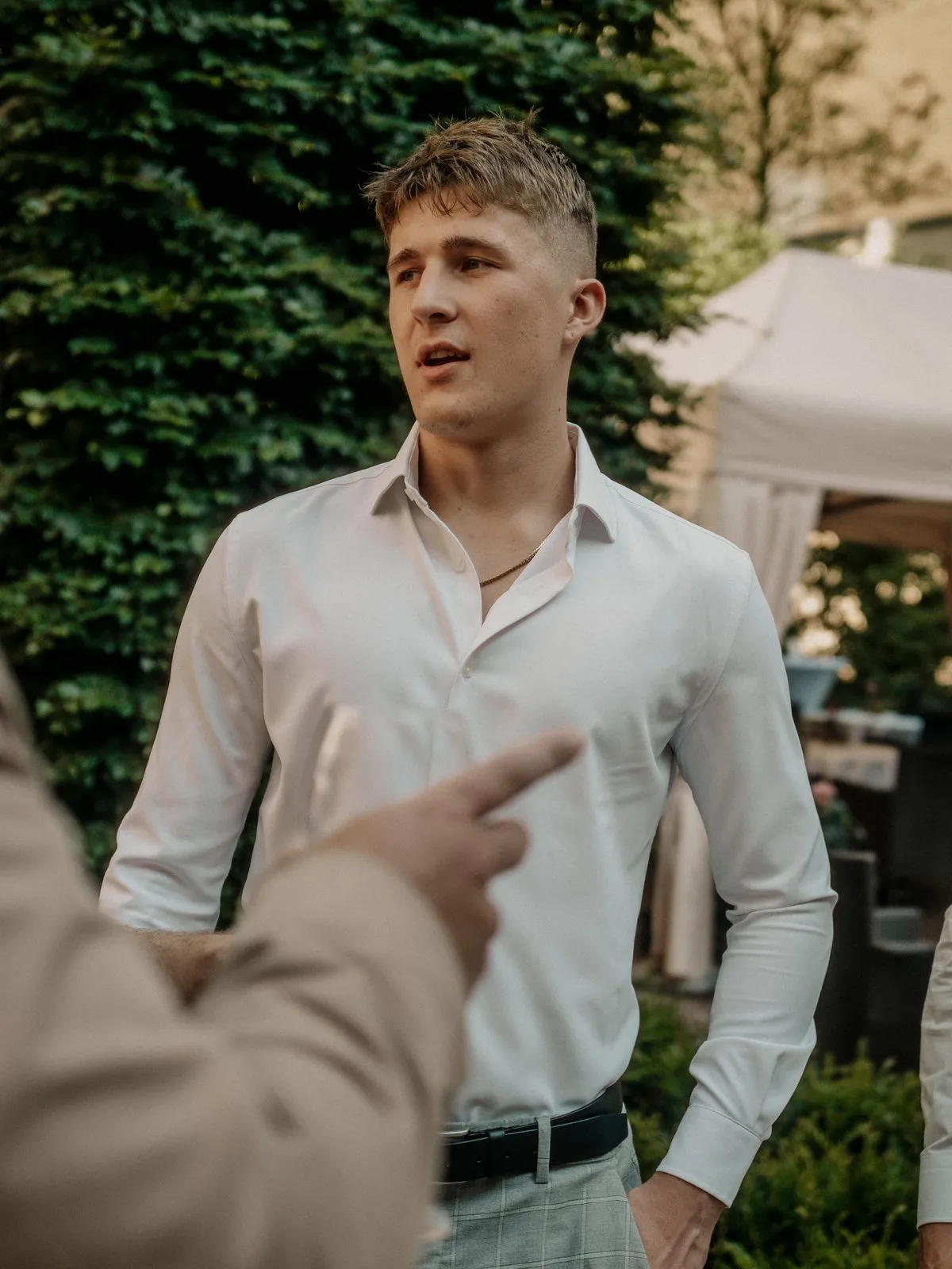 Lachlan in a white shirt, mid-conversation at an outdoor event